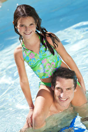 A father having fun with his daughter on his shoulders in a swimming poolの写真素材
