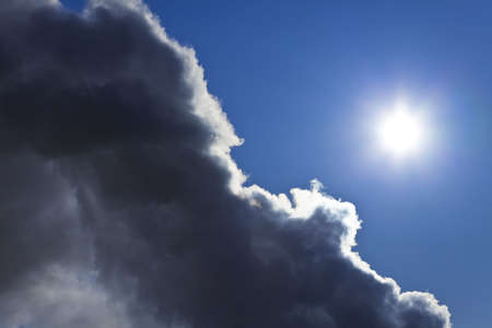 Photograph showing the sun and blue sky emerging from behind a storm cloud.の写真素材