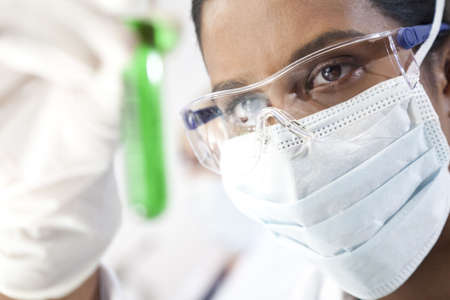 Environmental concept shot of a female Asian medical or scientific researcher or doctor looking at a test tube of a green solution in a laboratory.の写真素材