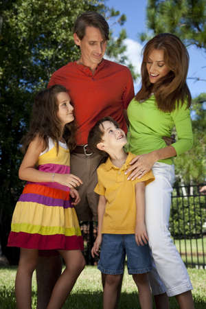 A modern family of father, mother, daughter and son playing together and having fun in a parkの写真素材