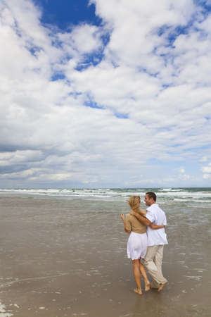 A young man and woman couple having romantic walk on a beach の写真素材