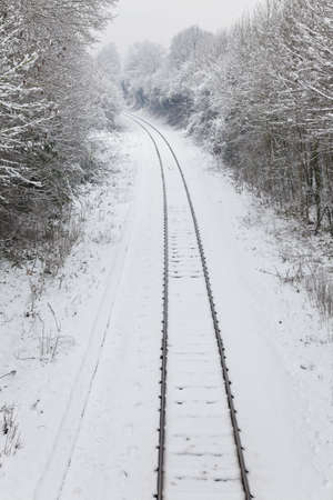 Snow covered railway tracks curving away around a corner into the distanceの写真素材