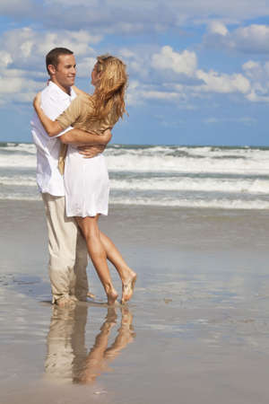 A young man and woman having fun as a romantic couple on a beachの写真素材