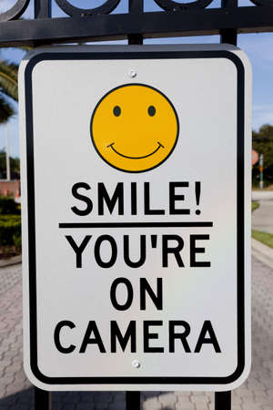 A Smile You're on Camera sign affixed to security gatesの写真素材