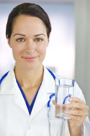 Healthy eating or lifestyle concept shot of a smiling female woman doctor holding and a glass of clear fresh waterの写真素材