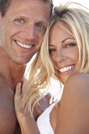 A sexy and attractive man and woman couple smiling and happy in the sunshine at the beachの写真素材
