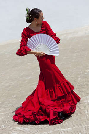 Woman traditional Spanish Flamenco dancer dancing in a red dress with a white fanの写真素材
