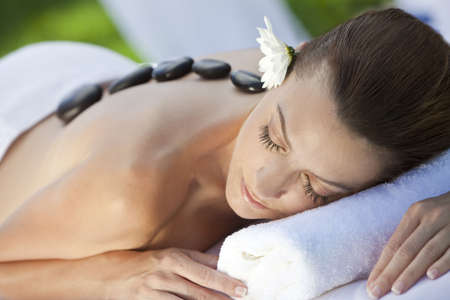 A woman relaxing at a health spa while having a hot stone treatment or massageの写真素材