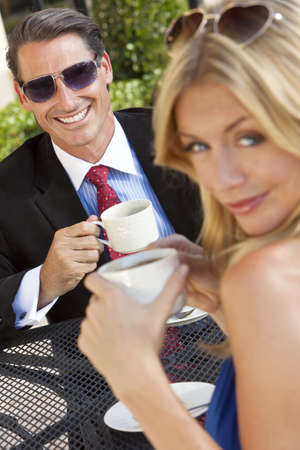 An happy handsome businessman and attractive woman couple having coffee togther at an outdoor cafe or retsaurant tableの写真素材
