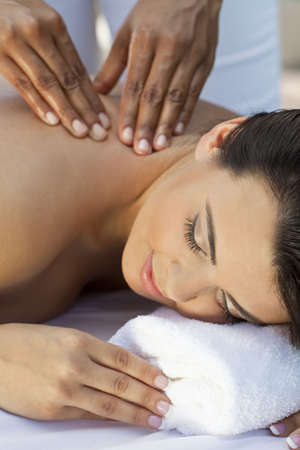 A young woman relaxing at a health spa while having a massageの写真素材