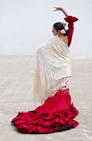 Woman traditional Spanish Flamenco dancer dancing outside in a red dress with a cream colored shawlの写真素材