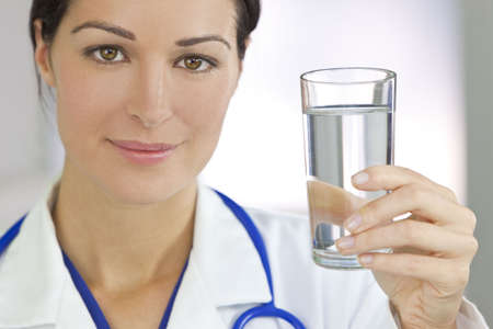 Healthy eating or lifestyle concept shot of a smiling female woman doctor holding and a glass of clear fresh waterの写真素材