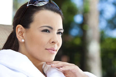 Portrait of a beautiful young Latina Hispanic woman smiling in a white bathrobe outside at a health spaの写真素材