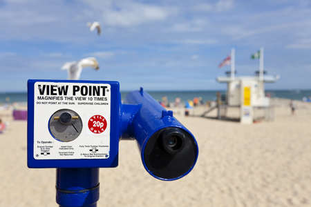 A coin operated telescope viewpoint on a classic British beach during the summer with seagulls flying pastの写真素材