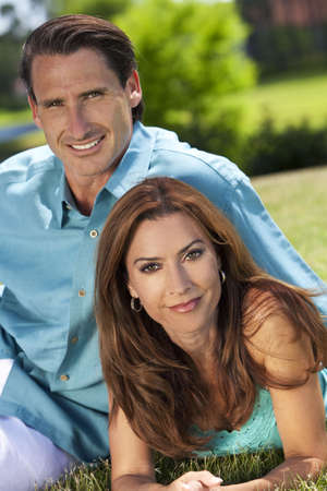 Portrait shot of an attractive, successful and happy middle aged man and woman couple in their thirties, sitting together outside and smiling.の写真素材