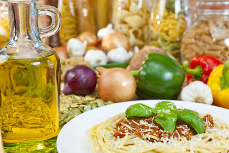 Spaghetti Bolognese with olive oil, Parmesan cheese, basil garnish various Italian pasta and ingredients out of focus in the background.の写真素材