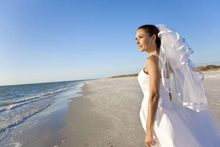 A married woman bride in her wedding dress in sunshine on a beautiful tropical beach の写真素材