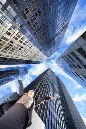 High Dynamic Range HDR photograph if a businesswoman arms raised surrounded by modern city high rise...