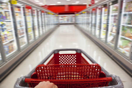 A fast food concept motion blur shot of a shopping trolley being pushed down the aisle of a supermarketの写真素材