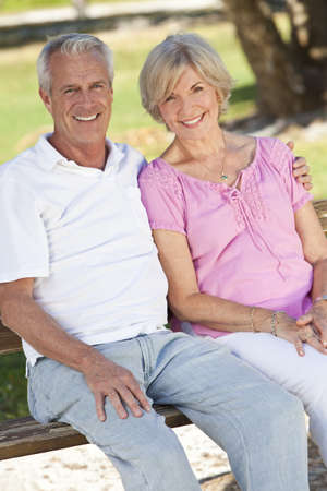 Happy senior man and woman couple sitting together outside in sunshineの写真素材