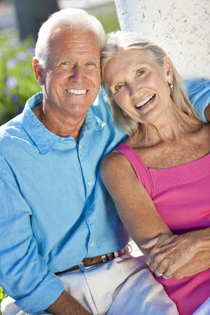 Happy senior man and woman couple sitting together outside in sunshineの写真素材