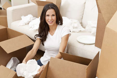 A beautiful single young woman unpacking boxes and moving into a new home.の写真素材