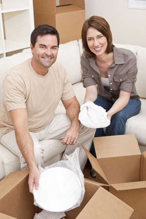 Happy couple in their thirties unpacking or packing boxes and moving into a new home.の写真素材