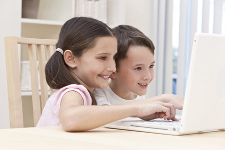 Young boy & girl children using laptop computer at home