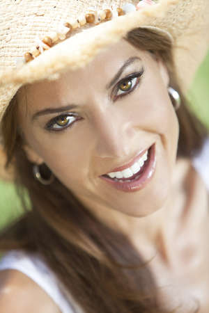Outdoor portrait of a beautiful young brunette woman in her thirties wearing straw cowboy hatの写真素材