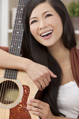A beautiful happy young Chinese Asian Oriental woman with a wonderful toothy smile holding her...