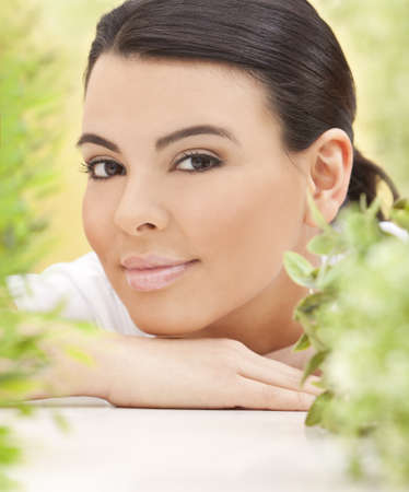 Spa concept beautiful Hispanic woman smiling surrounded in natural green leavesの写真素材