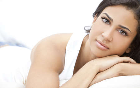Studio portrait of a beautiful young Latina Hispanic young woman or girl looking thoughtful resting on her handsの写真素材