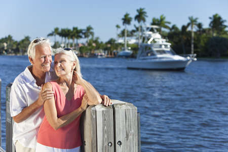 Happy senior man and woman couple together by a river or sea in a tropical location with a boat sailing pastの写真素材