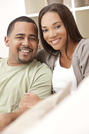 A happy African American man and woman couple in their thirties sitting at homeの写真素材