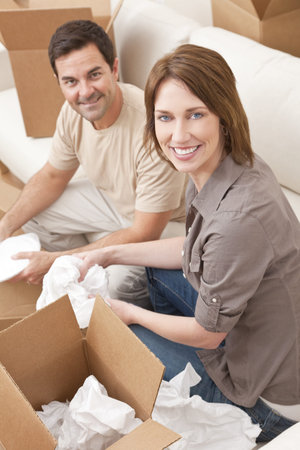 Happy couple in their thirties unpacking or packing boxes and moving into a new home 