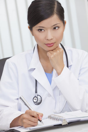 A Chinese Asian female medical doctor writing in a hospital office