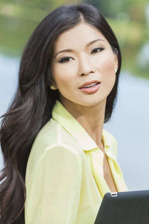 Beautiful Asian Chinese young woman or girl outside holding tablet computerの写真素材