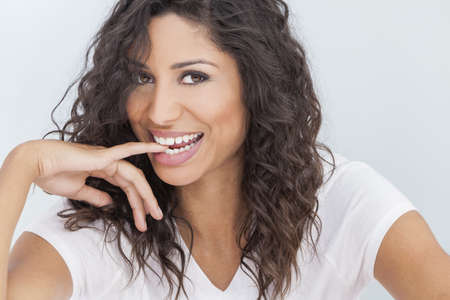 Studio portrait of a beautiful young mixed race Latina Hispanic woman smiling and biting her finger with perfect teethの写真素材