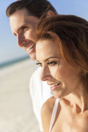Middle aged man & woman couple together in sunshine on a beautiful tropical beachの写真素材