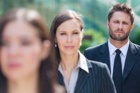 A young businessman business man with beard waiting behind two businesswomen in line