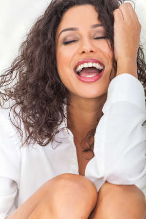 Beautiful young sexy happy Latina Hispanic woman with perfect teeth open mouthed laughing in ecstasyの写真素材