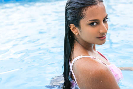 Beautiful sexy young Indian Asian woman or girl wearing bikini in swimming poolの写真素材