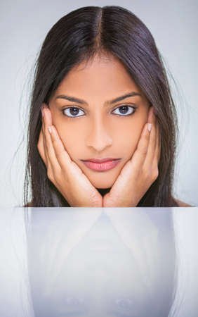 Portrait of a beautiful young Indian Asian woman or girl resting on her hands with reflectionの写真素材