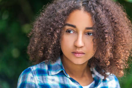 Outdoor portrait of beautiful happy mixed race African American girl teenager female child looking thoghtful or sadの写真素材