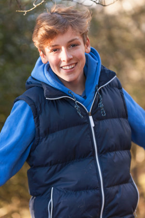 Young happy laughing male boy teenager blond child young adult outside in a wood or forest in autumn...