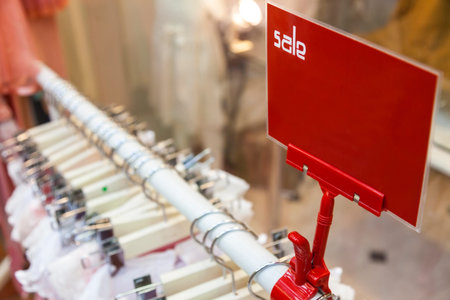 A red sale sign on rail of clothes in a shopの写真素材
