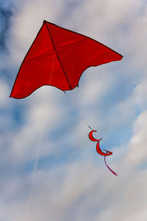 Red kite flying in blue sky with cloudsの写真素材