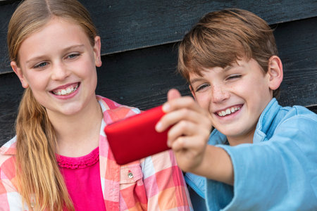 Two children boy and girl talking cell phone selfie photograph