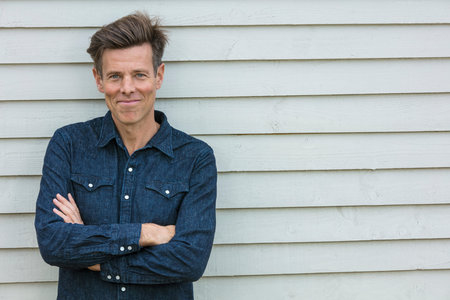 Portrait shot of an attractive, successful and happy middle aged man male arms folded outside...