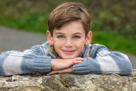Young happy laughing male boy blond child outside leaning on his hands in autumn fall sunshine の写真素材